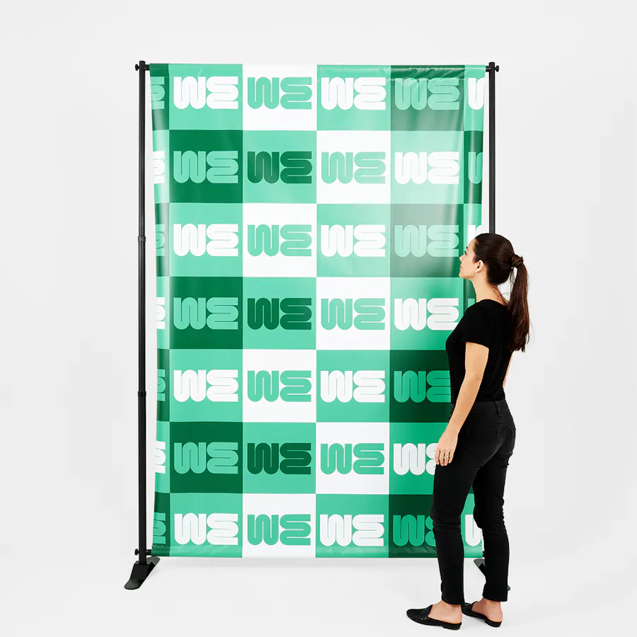 A woman wearing a black outfit standing next to a green and white step and repeat banner.