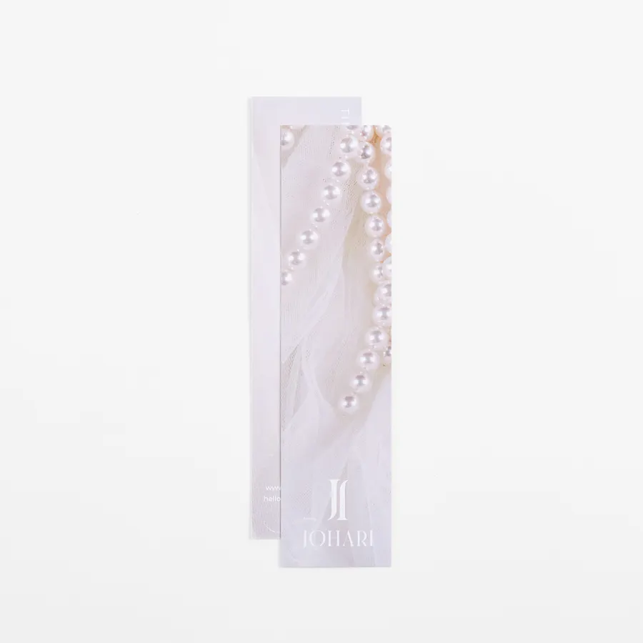 Two custom bookmarks overlapping each other and printed with JOHARI in white and a pearl necklace.