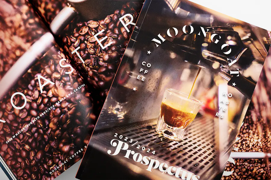 A pile of business prospectuses for MoonGoat Coffee printed with a perfect binding and coffee bean images.