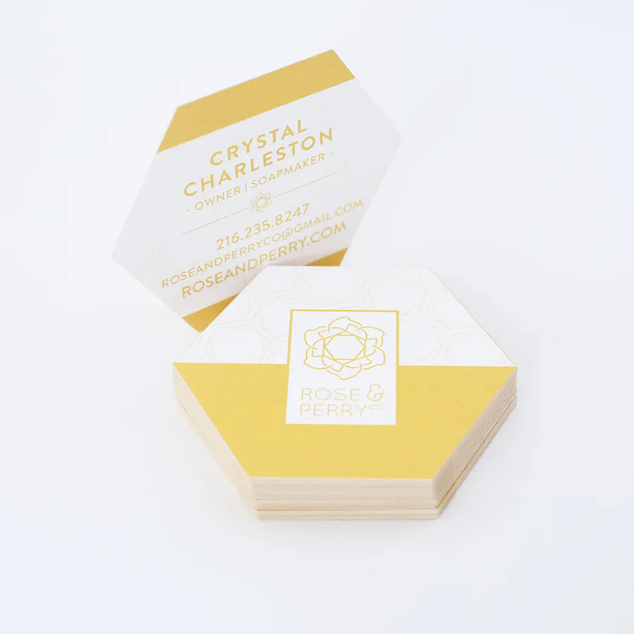 A stack of unique business cards printed with a hexagon shape and yellow and white design.