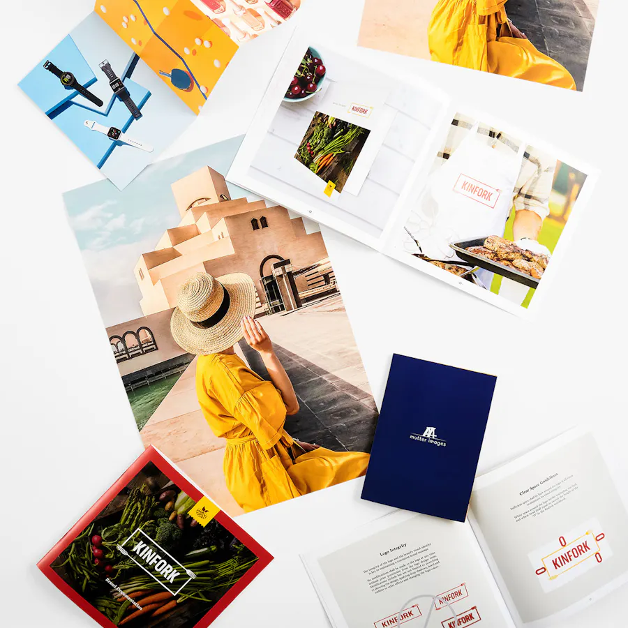 Scattered print marketing materials with various designs on a coated paper stock.