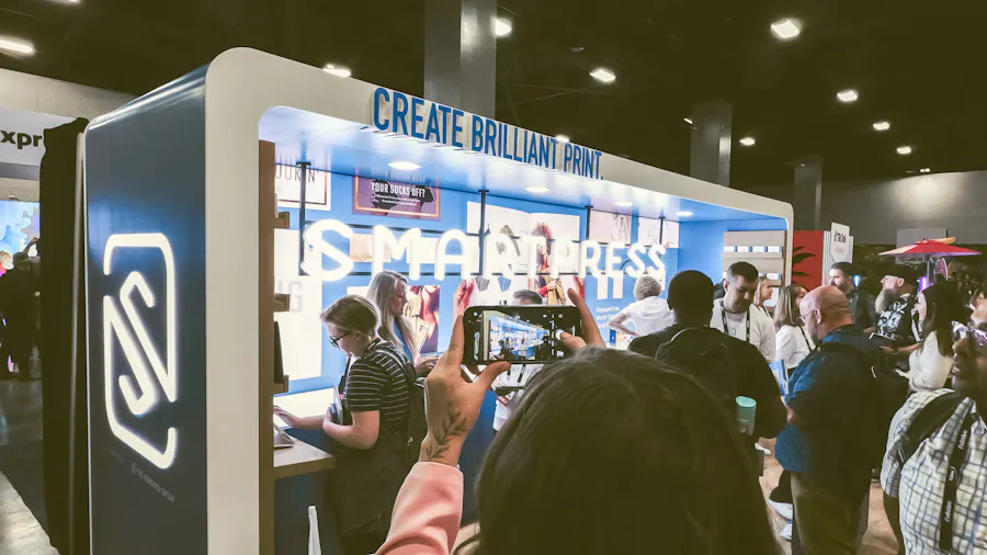 The Smartpress booth at the Adobe MAX Creativity Conference with a crowd of attendees talking and taking pictures.