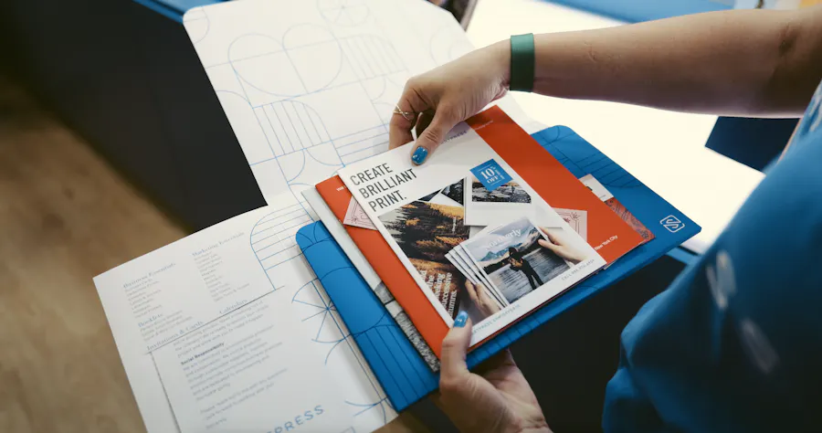 A person holding a branded folder filled with various printed brochures and booklets.