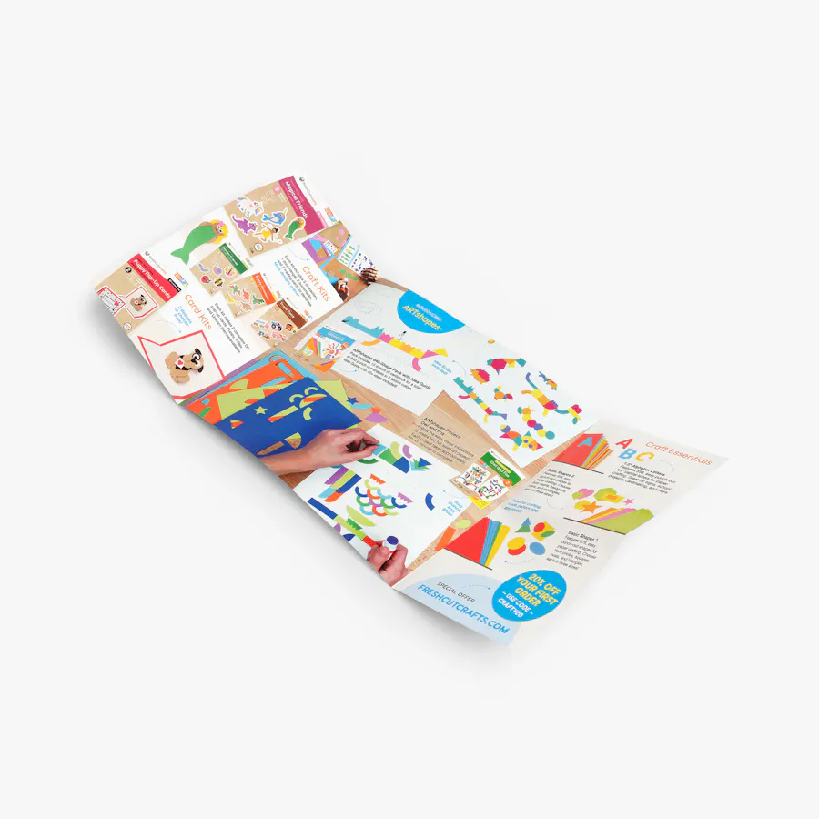 An unfolded right angle fold mailer printed with bright, colorful imagery of crafting supplies.