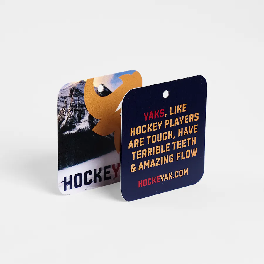 Two rack cards overlapping each other and printed as apparel tags for the HOCKEYAK brand.