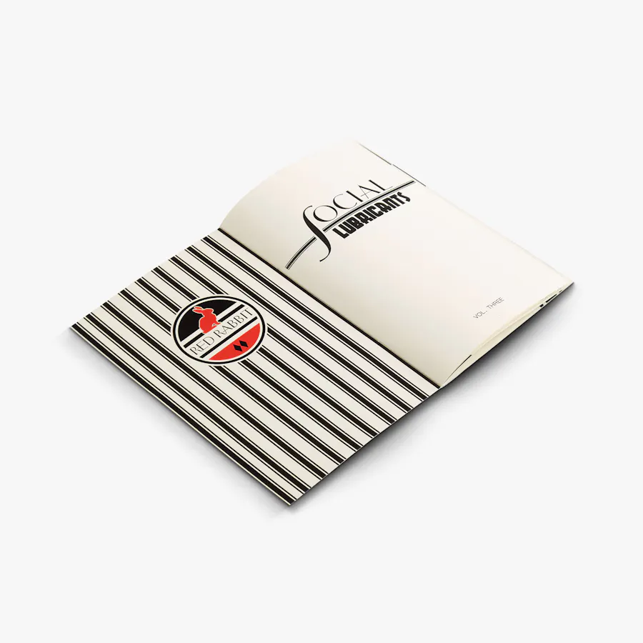 A restaurant menu laying open and printed with a Red Rabbit logo and Social Lubricants in black, white and red.