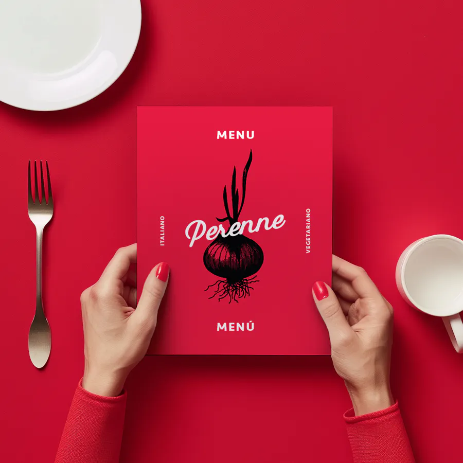 Two hands holding a restaurant menu in bright red over a red tablecloth with a plate, fork and cup around it.