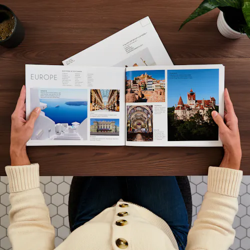 Travel Saddle Stitch Booklet Two hands holding a travel catalog open to images of European destinations.