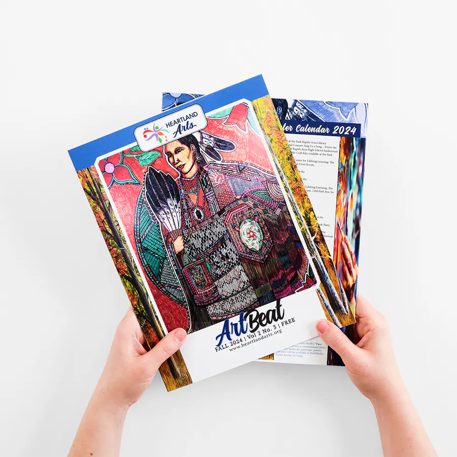 Two hands holding two marketing magazines printed with Art Beat on the cover.