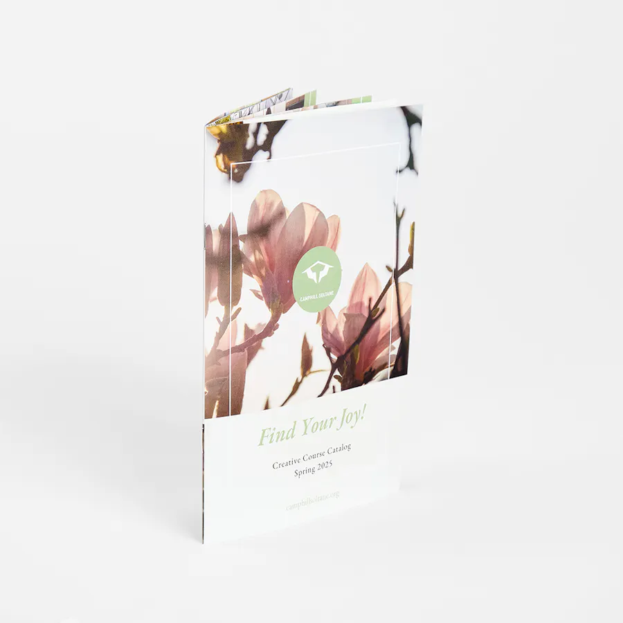 A custom magazine standing open and printed with Find Your Joy and course catalog information.