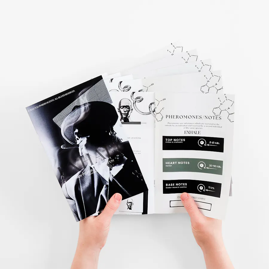 Two hands holding multiple magazines fanned out and printed with fragrance information.