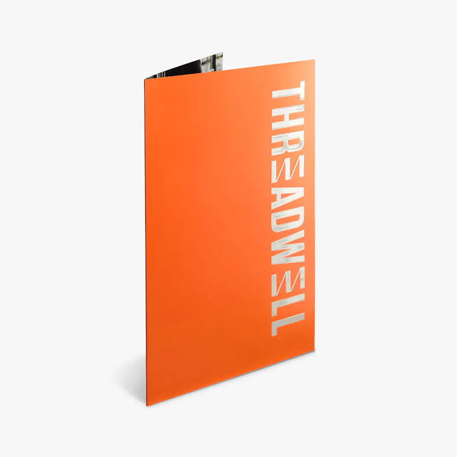 A pocket folder standing open and printed with an orange background and Threadwell in raised UV.