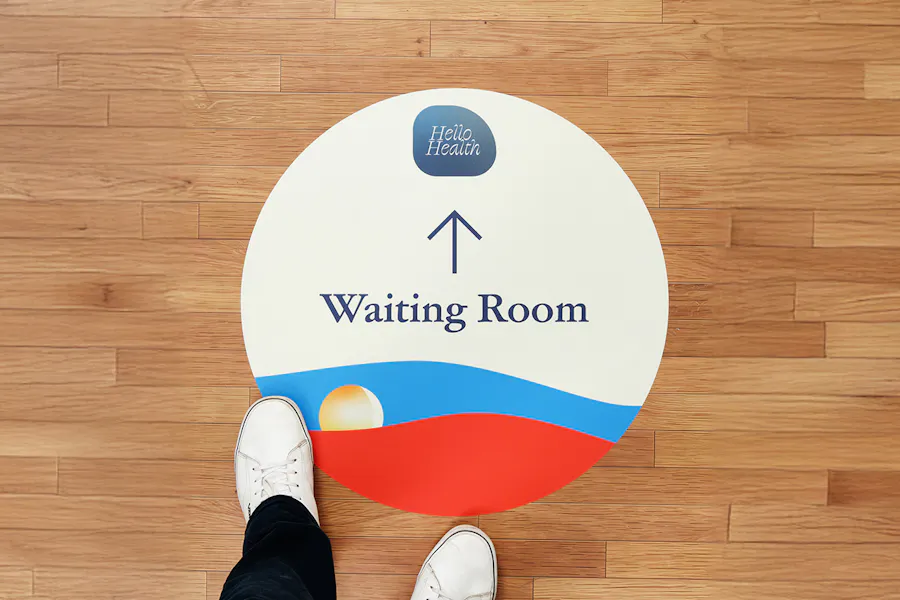 Two feet standing on a floor graphic printed with Waiting Room and Hello Health in blue.