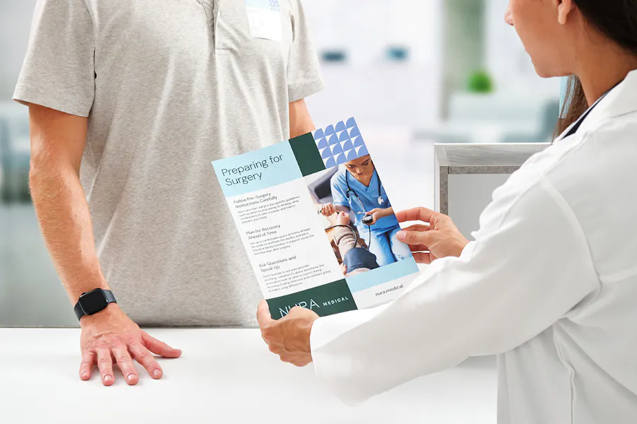 A female doctor giving a patient education sheet with surgery details to a patient.