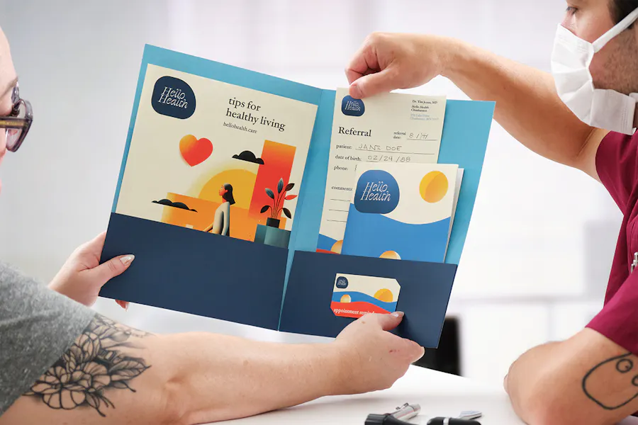 A nurse and patient looking at health care marketing materials in a blue pocket folder.