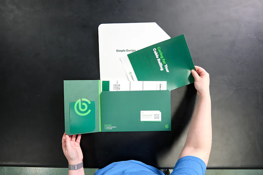 Two hands holding a green marketing folder full of matching printed assets.