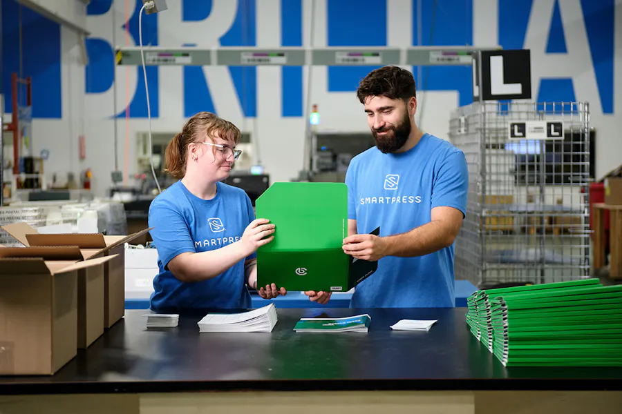 A man and woman in a Smartpress production facility kitting together marketing folders.