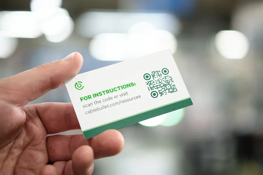 A hand holding a business card printed with a QR code for railing install instructions.