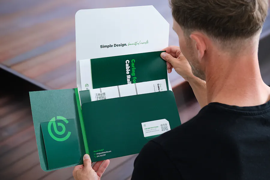 A man holding a branded folder full of coordinating print marketing assets.