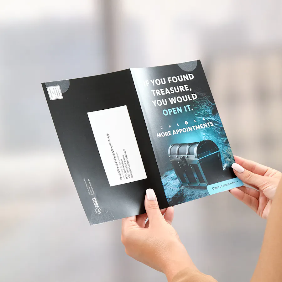 Two hands holding open a marketing mailer printed with messaging and imagery for Phone Ninjas.