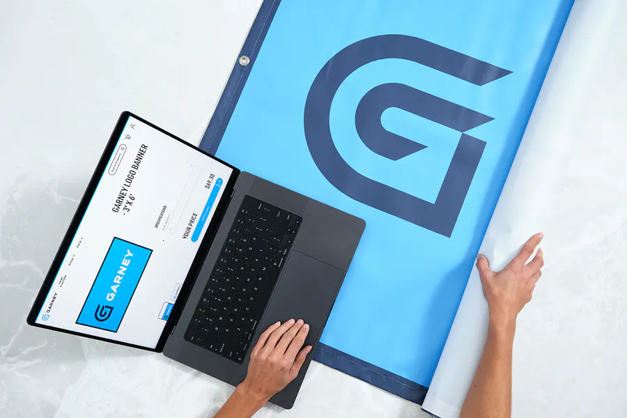 A laptop showing the MOD print management software sitting on a Garney hanging banner.