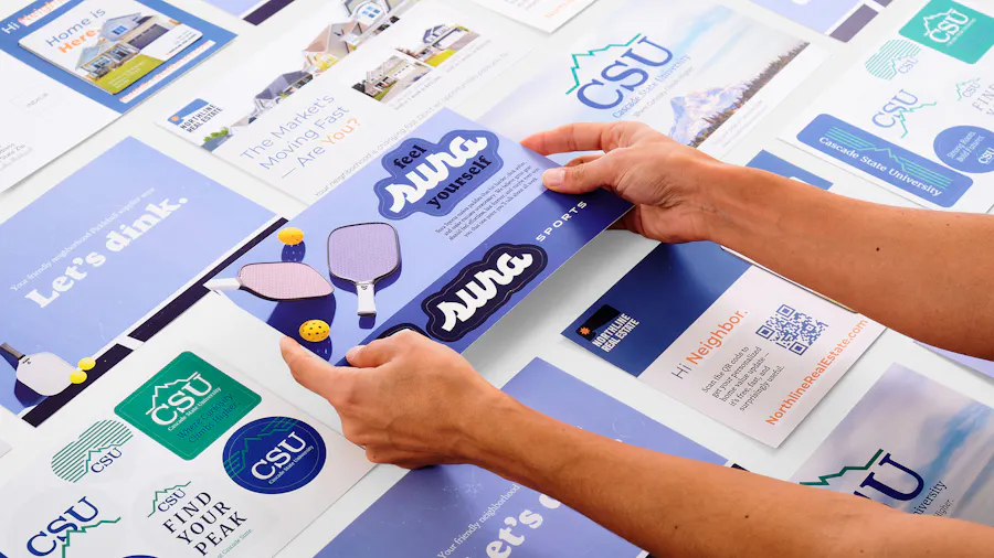 Two hands holding a sticker postcard with pickleball stickers among more postcards.