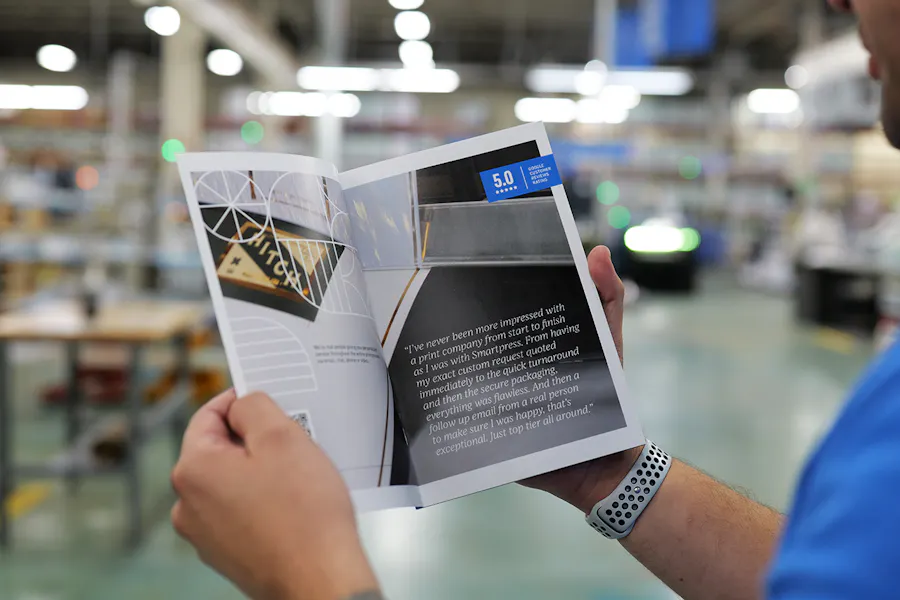 A person in a production facility holding a Smartpress custom catalog printed with a quote from a customer.