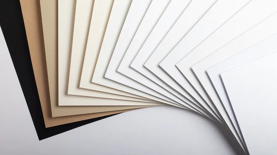 Paper stocks fanned out in an arc, ranging from shades of white to shades of tan to black.