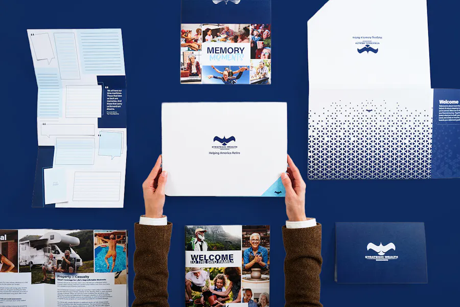 Two hands holding a branded folder with welcome kit booklets and brochures around it.