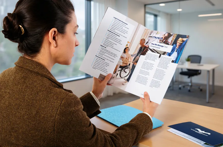 A woman sitting at a table and looking at a materials from a printed welcome packet.