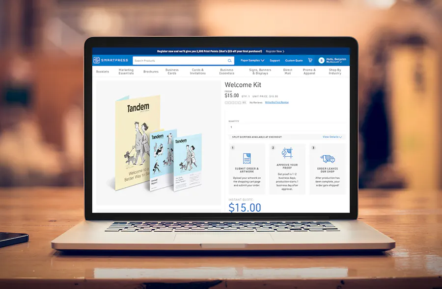 A laptop sitting on a wooden table showing Smartpress' website on a Welcome Kit product page.