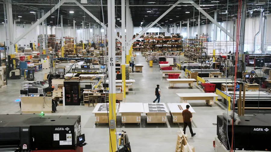 The Smartpress online printing production floor, with printing presses and employees walking around.