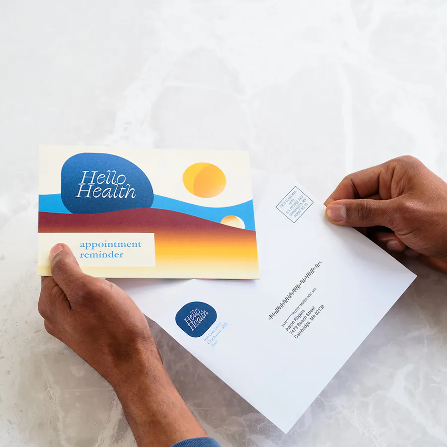 Two hands holding an appointment reminder direct mail card and envelope.